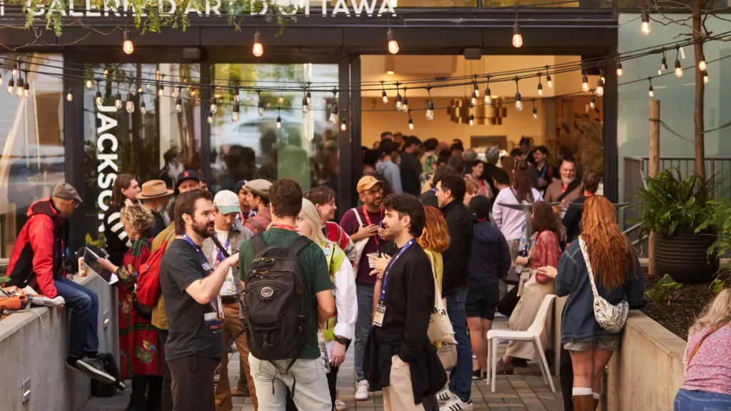 A lively group of individuals standing in front of a restaurant, engaged in conversation and socializing.
